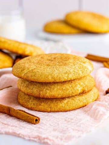 three snickerdoodle cookies with cinnamon sticks on the side.