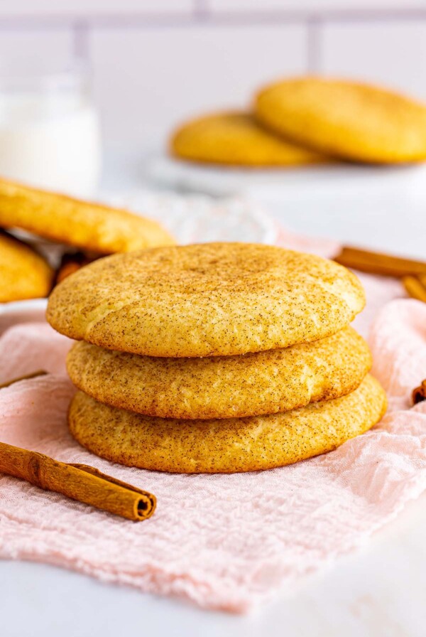 three snickerdoodle cookies with cinnamon sticks on the side.