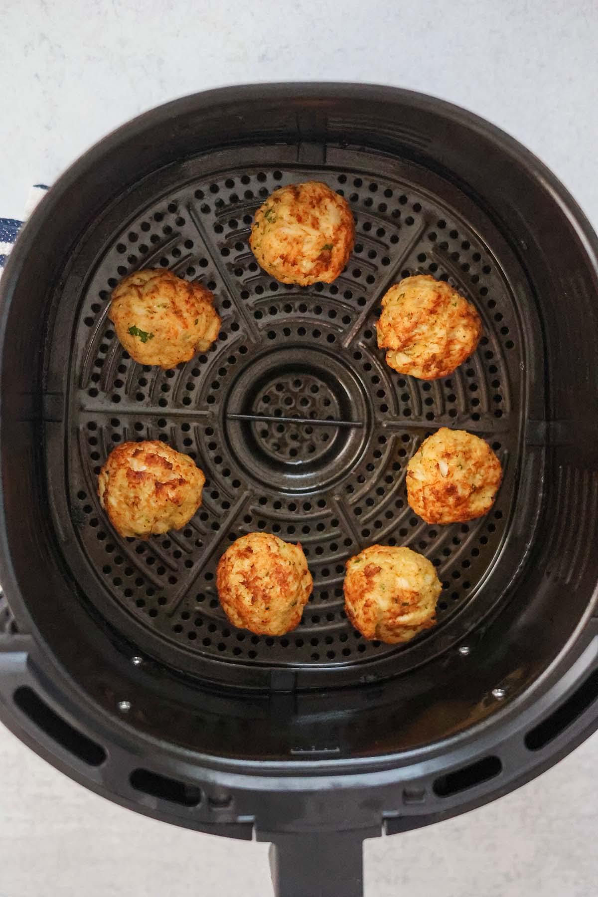 seven cooked crab bites in the air fryer basket. 