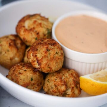 crab bites with a side of remoulade sauce and a lemon wedge.