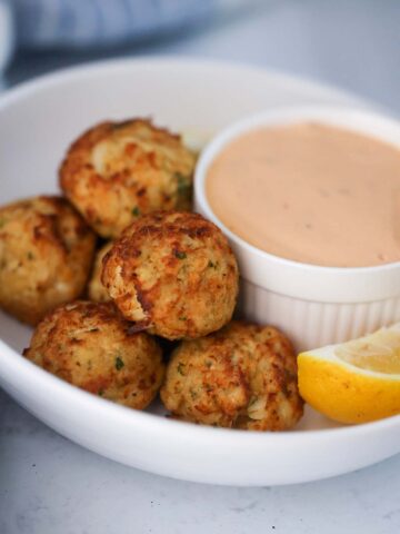 crab bites with a side of remoulade sauce and a lemon wedge.
