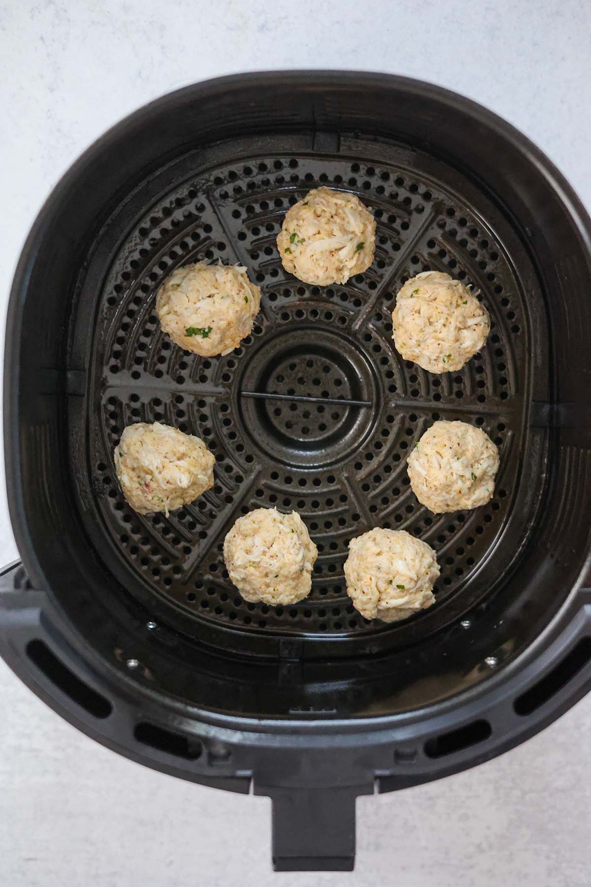 uncooked crab bites in the air fryer basket. 