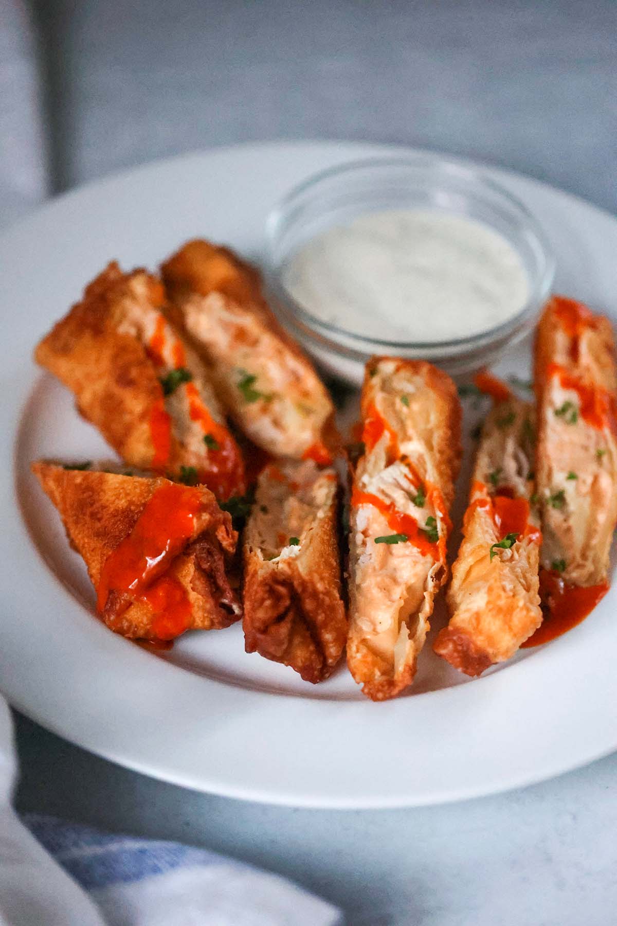 seven buffalo chicken egg rolls on a plate with ranch on the side. 