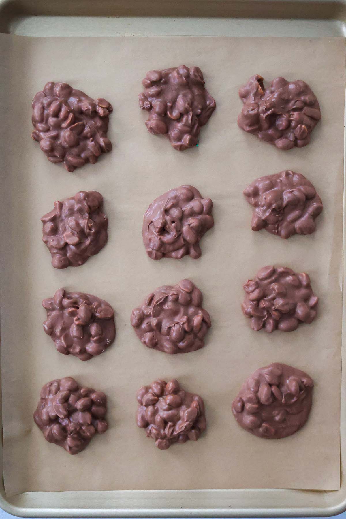 Twelve crockpot candies on a baking sheet. 