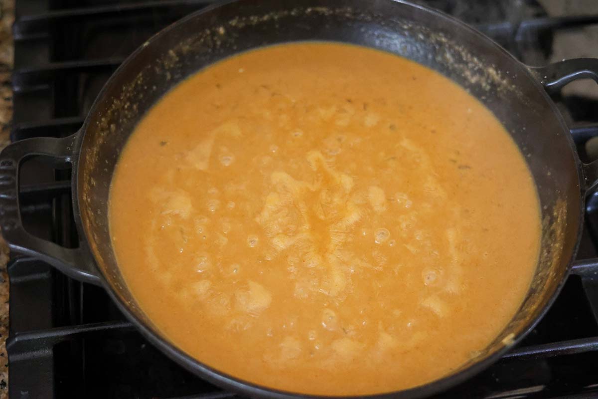 gravy simmering in a cast iron skillet on the stovetop. 