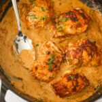 creamy spicy chicken thighs in a skillet with a spoon.