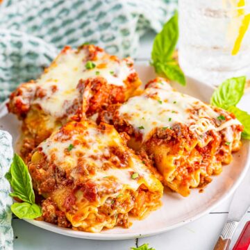 Three lasagna roll ups on a plate.