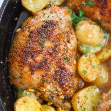 Roasted chicken thighs and potatoes in a cast iron skillet.