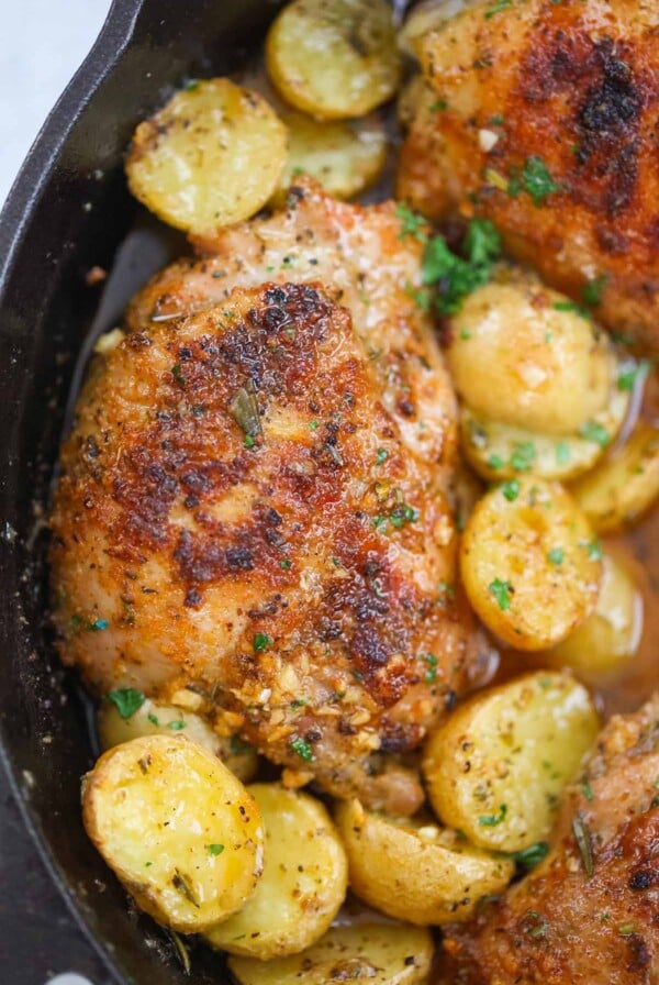 Roasted chicken thighs and potatoes in a cast iron skillet.