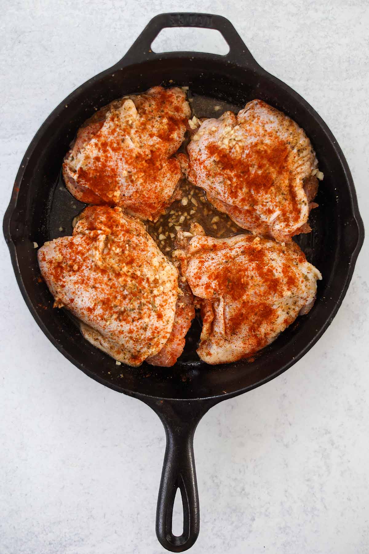 four raw chicken thighs in a cast iron skillet. 