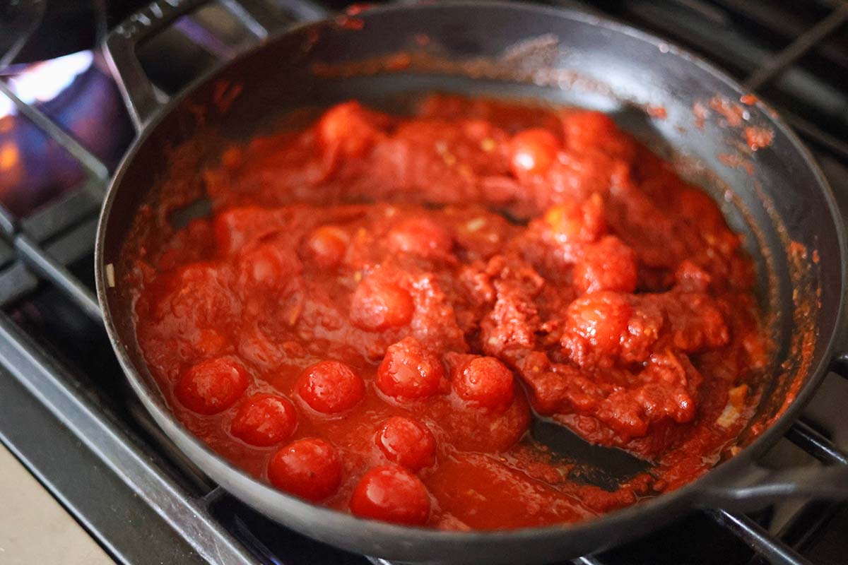 cherry tomatoes and tomato paste cooking in a skillet. 