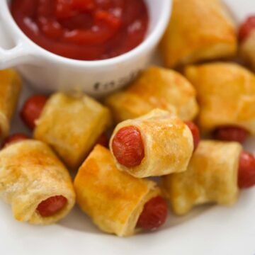 pigs in a blanket with ketchup on the side.