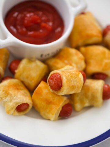 pigs in a blanket with ketchup on the side.