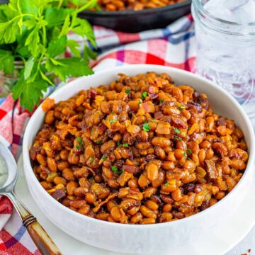 a bowl of baked beans with bacon on top.