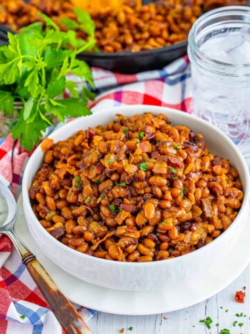 a bowl of baked beans with bacon on top.