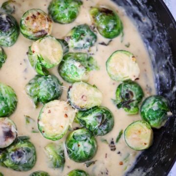 Creamy garlic brussels sprouts in a skillet up close.