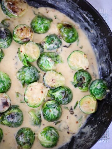 Creamy garlic brussels sprouts in a skillet up close.