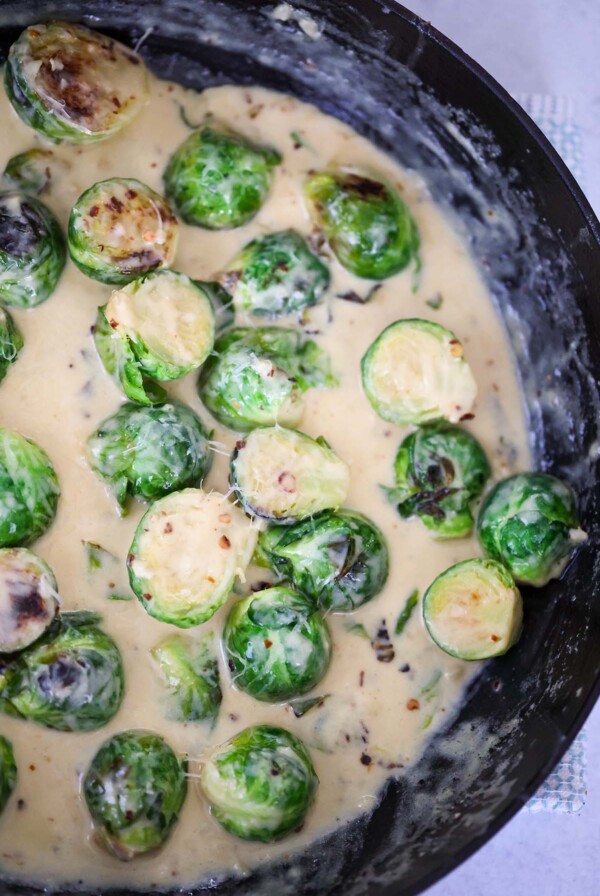 Creamy garlic brussels sprouts in a skillet up close.