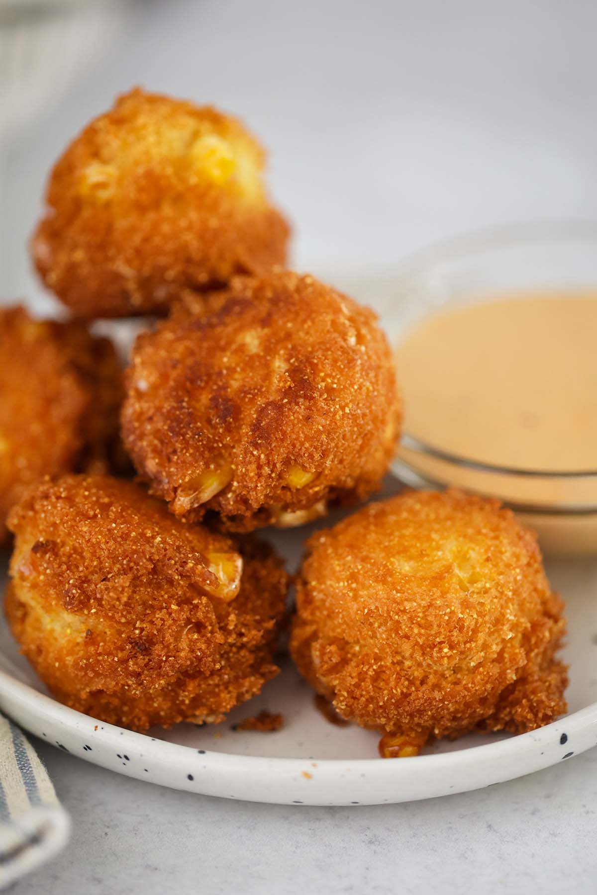 hush puppies on a small plate with sauce on the side. 