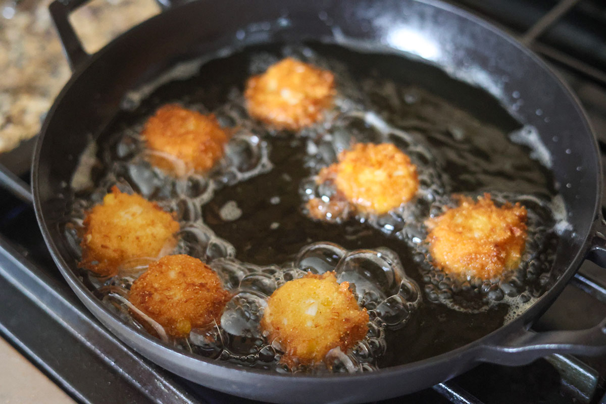 crab hush puppies frying in a skillet. 