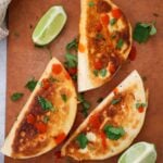 cheesy buffalo chicken tacos with lime wedges on the side.