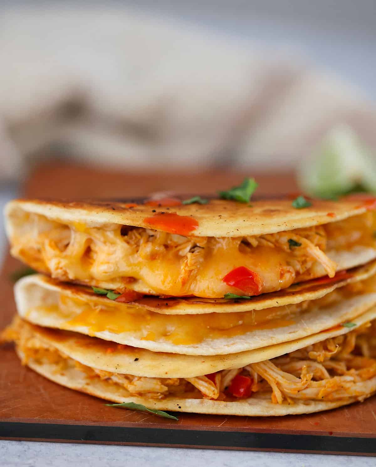 three buffalo chicken tacos stacked on a cutting board. 