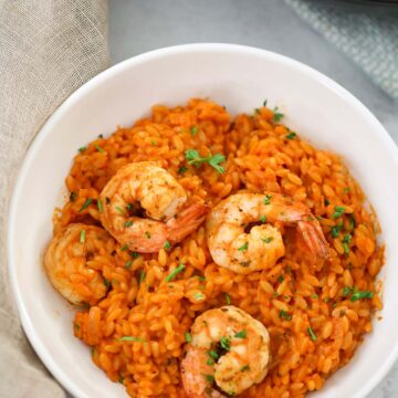 creamy tomato orzo with shrimp in a white bowl.