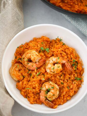 creamy tomato orzo with shrimp in a white bowl.