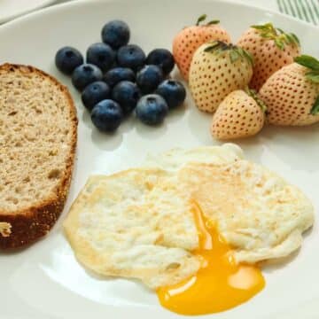 over easy egg with runny yolk, toast, and berries on the side.