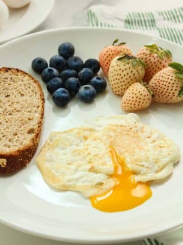 over easy egg with runny yolk, toast, and berries on the side.