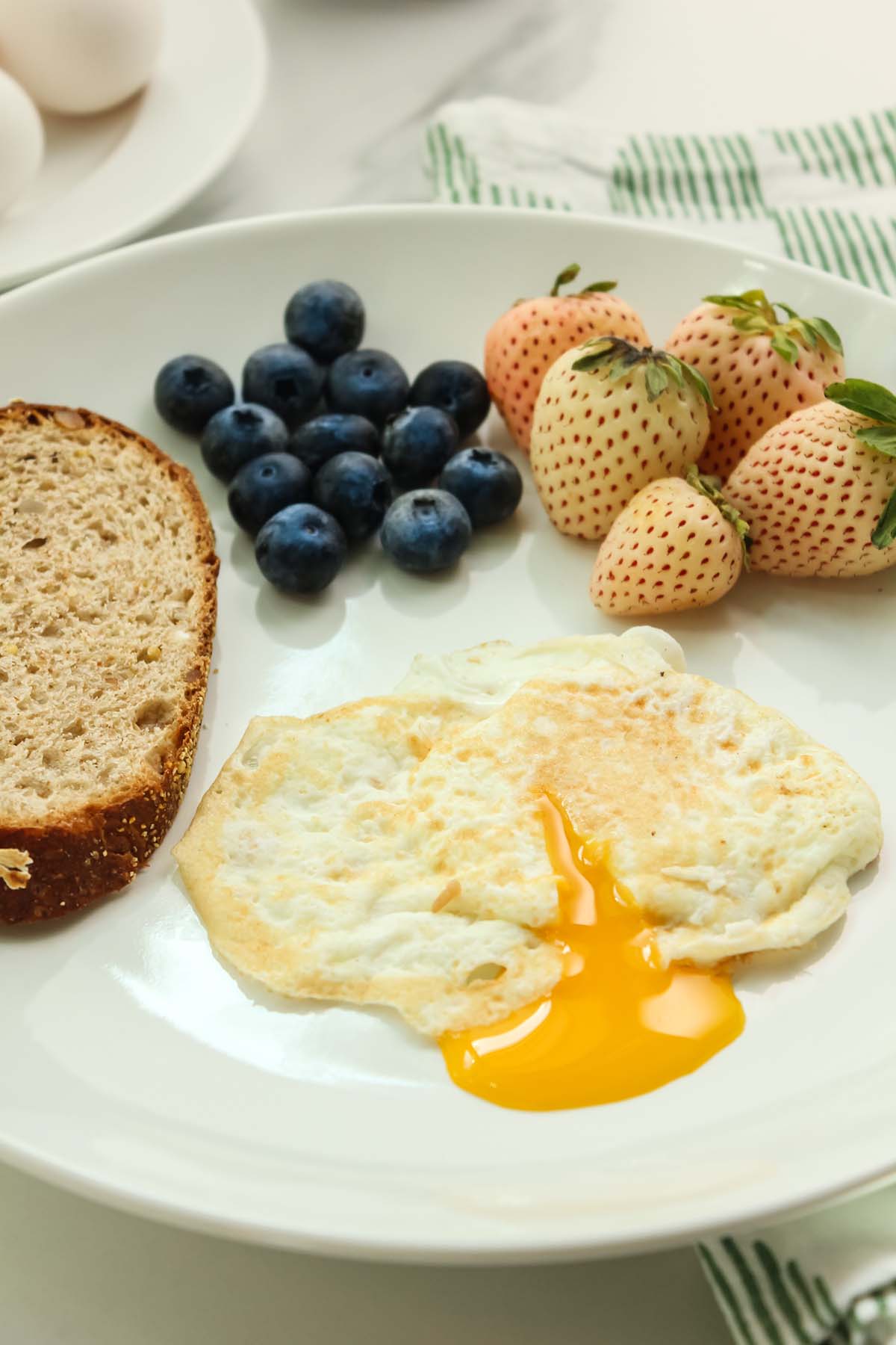 over easy egg with yolk coming out of egg, toast, and berries. 