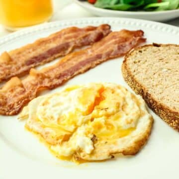 over medium egg with two strips of bacon and toast.