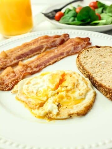 over medium egg with two strips of bacon and toast.