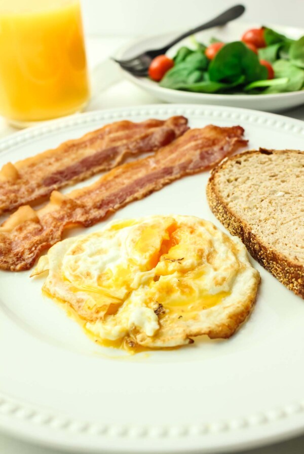 over medium egg with two strips of bacon and toast.