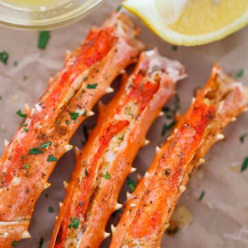 baked king crab legs with butter and lemon on the side.