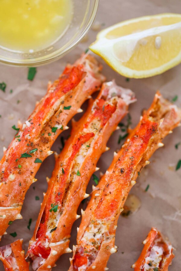 baked king crab legs with butter and lemon on the side.