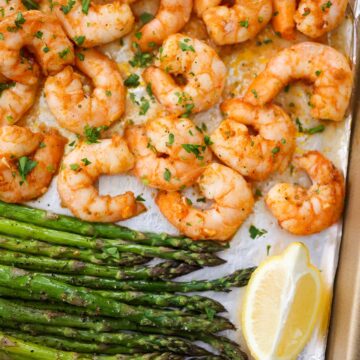 baked shrimp and asparagus with lemon wedges.