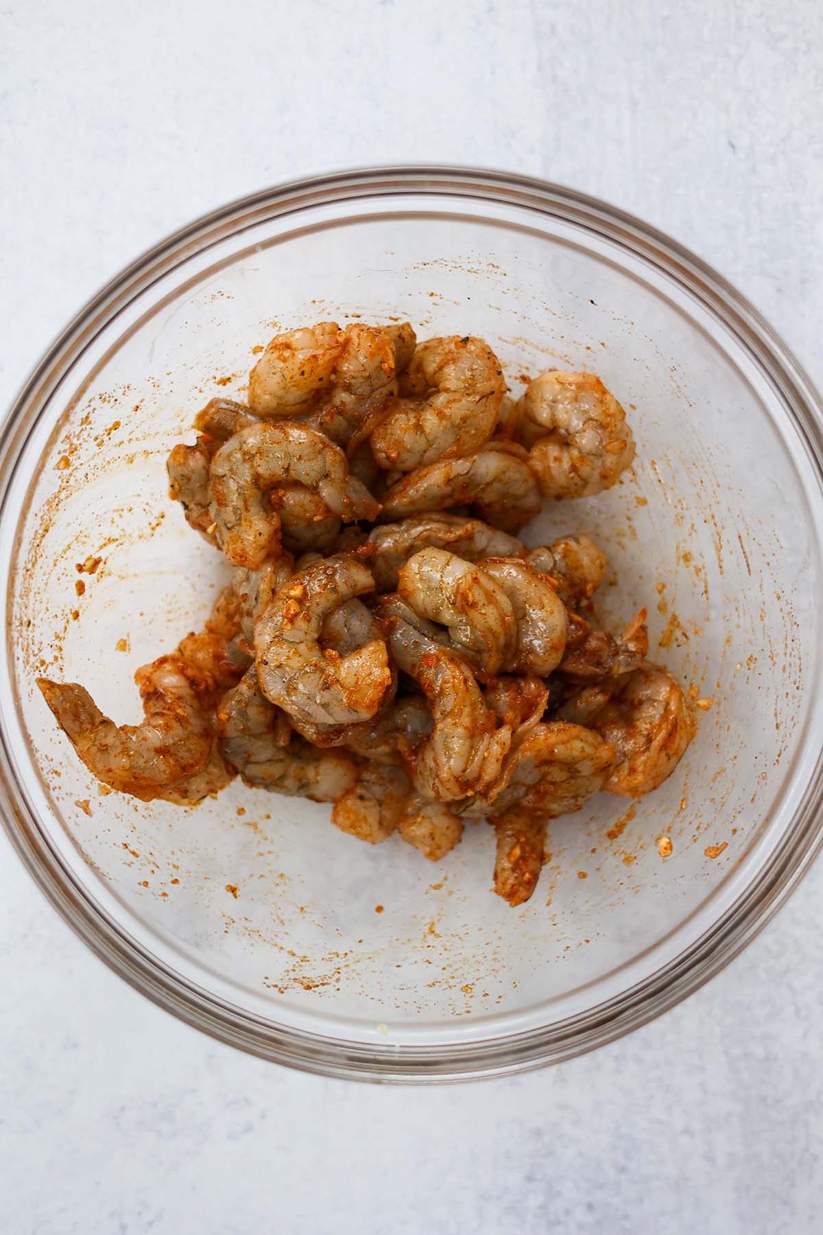raw shrimp coated in oil and spices in a bowl.