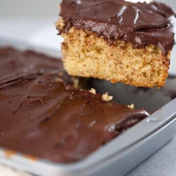 A slice of banana cake with chocolate frosting.