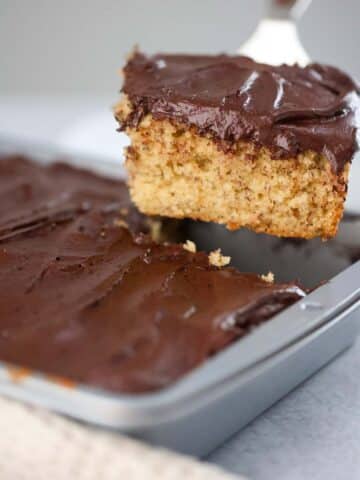 A slice of banana cake with chocolate frosting.