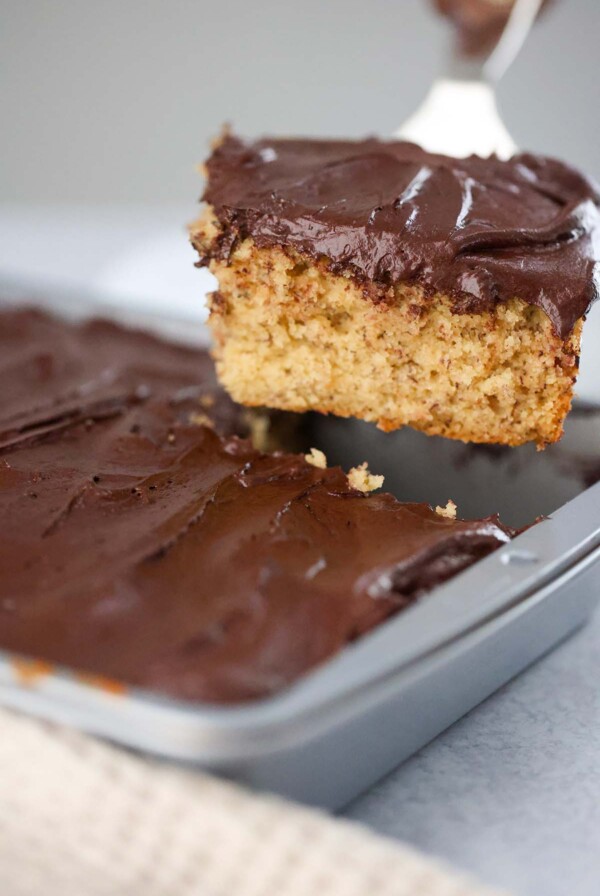 A slice of banana cake with chocolate frosting.