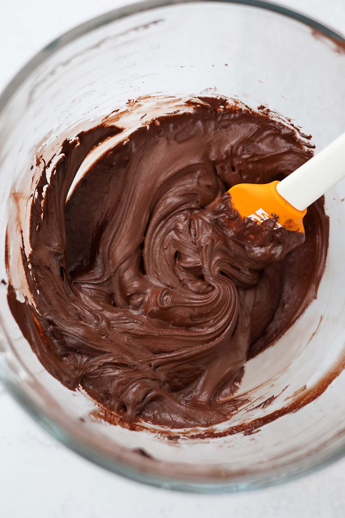 chocolate frosting in a mixing bowl with a spatula. 