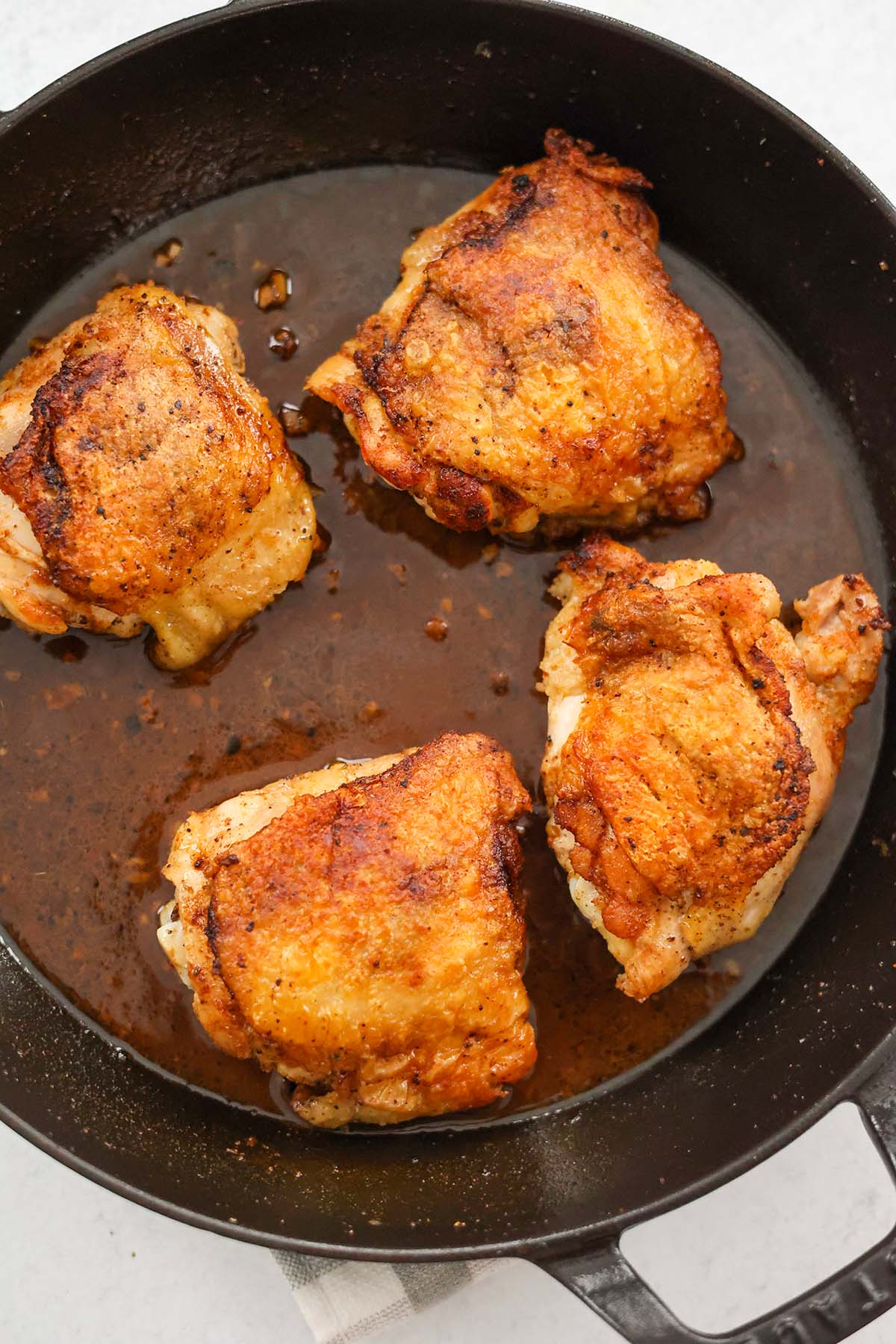 four pan-seared chicken thighs in a cast iron skillet. 