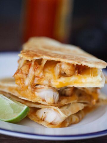 shrimp quesadillas on a plate with a lime wedge on the side.