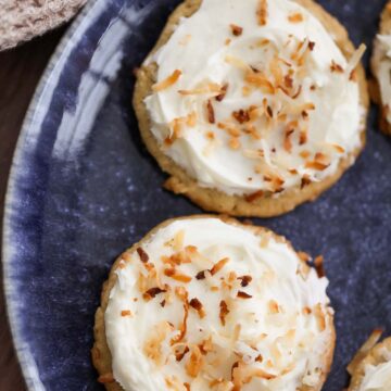 two coconut cookies with cream cheese frosting on a blue plate.