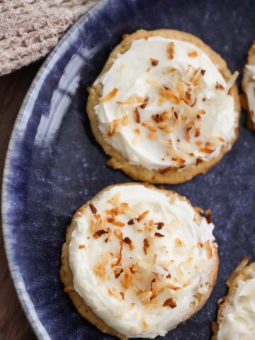 two coconut cookies with cream cheese frosting on a blue plate.