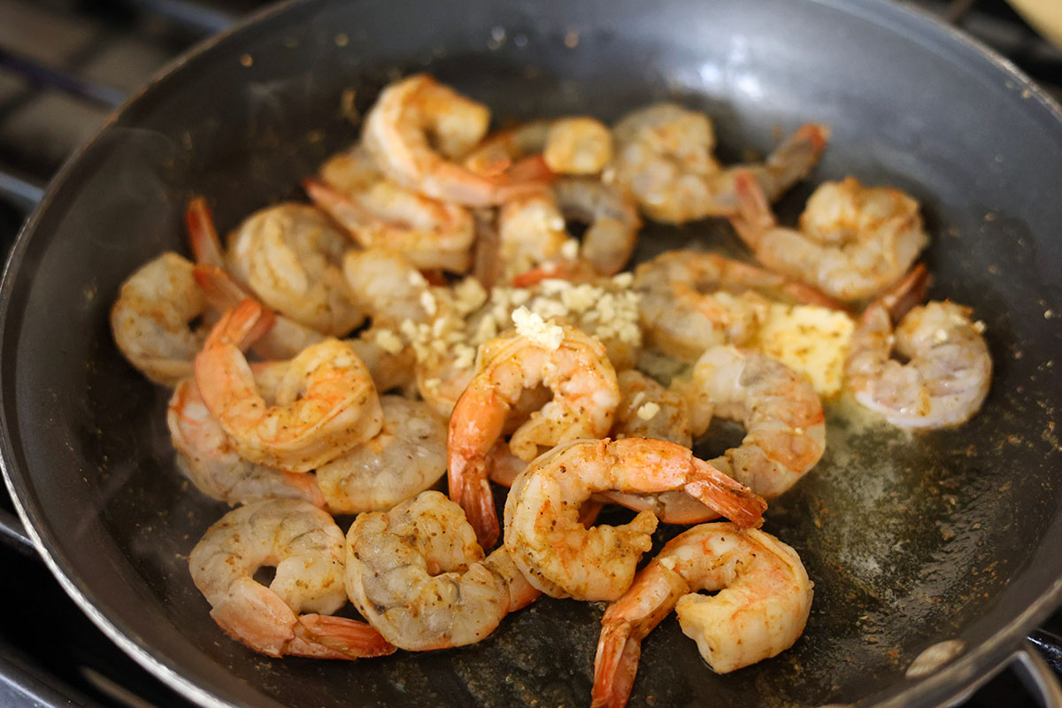 shrimp and garlic cooking in a skillet on the stovetop. 