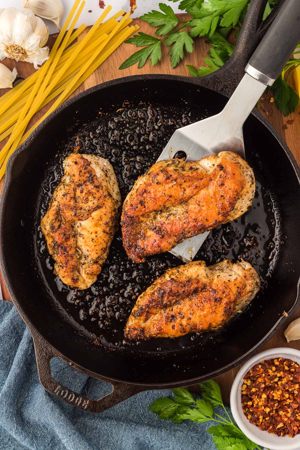 three pan seared chicken breasts in a cast iron skillet.