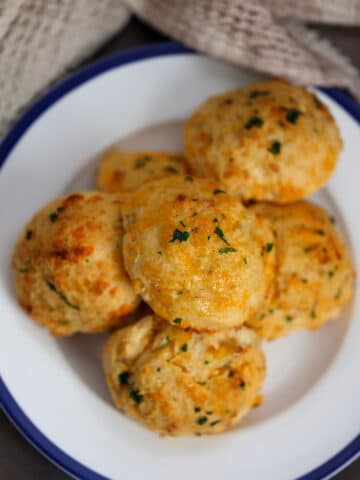 six red lobster cheddar biscuits on a white and blue plate.