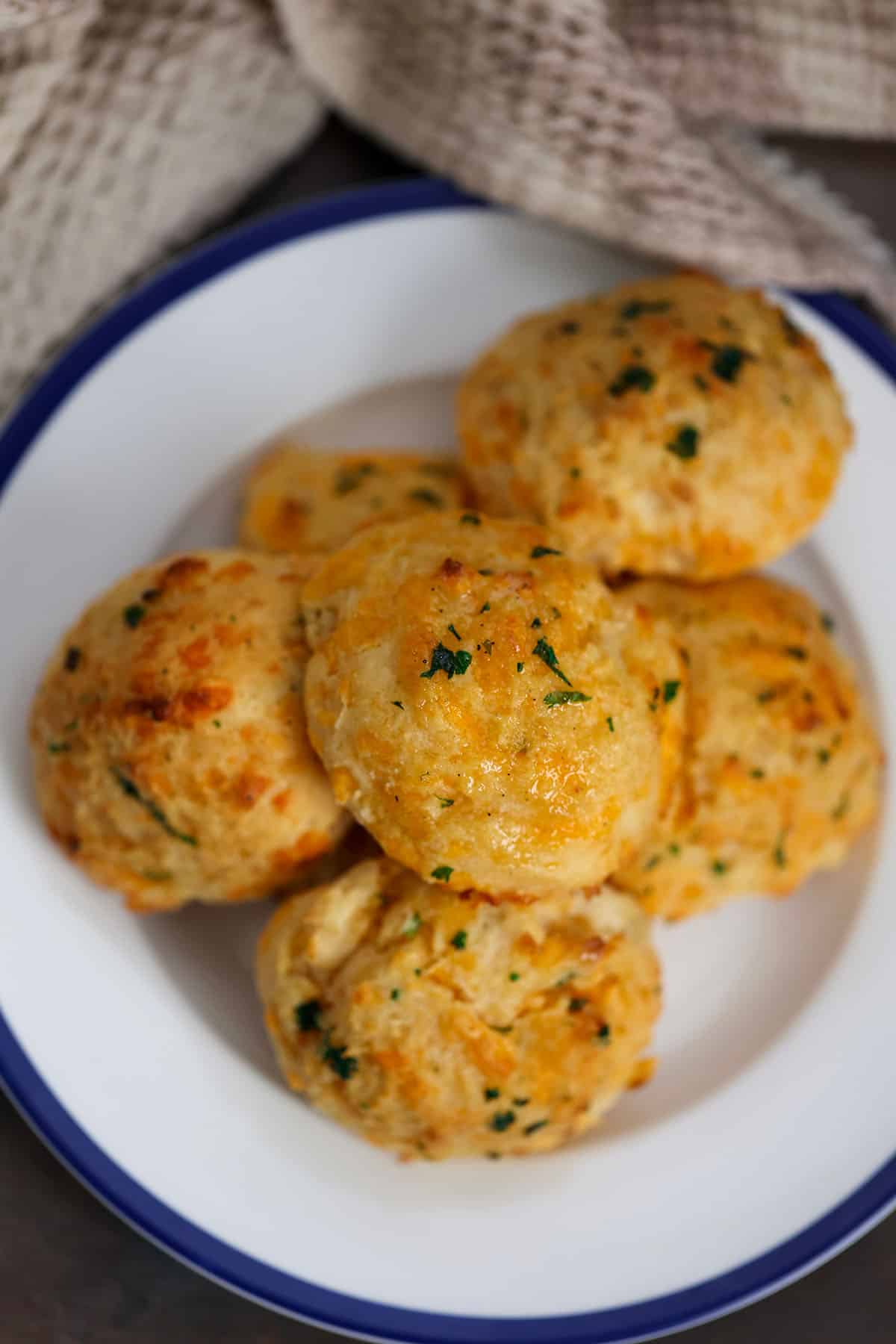 six red lobster cheddar biscuits on a white and blue plate. 